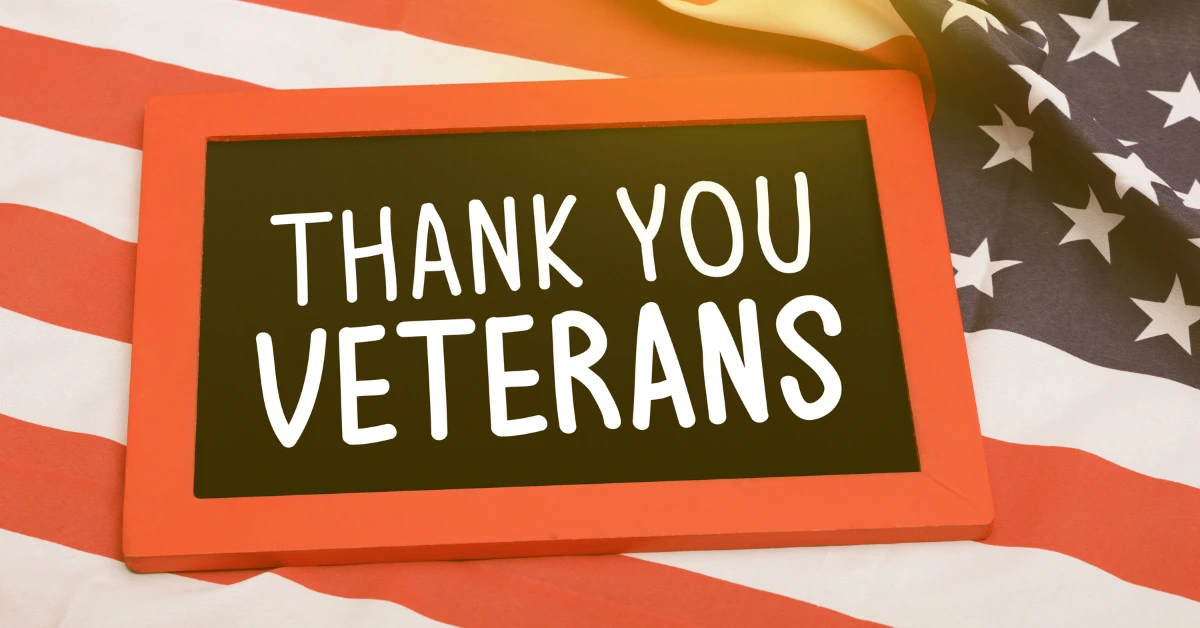“Thank You Veterans” message displayed on a framed sign placed over a folded American flag in a patriotic setting.