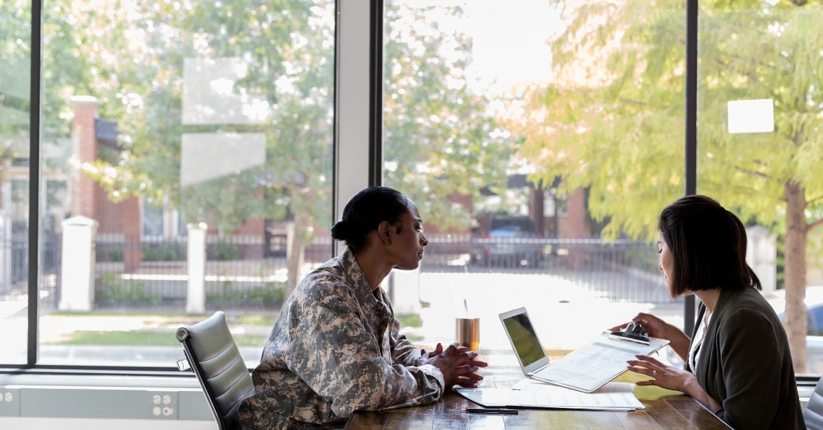 Service member meeting with a clinician to discuss VA behavioral health referral options in a professional office setting.