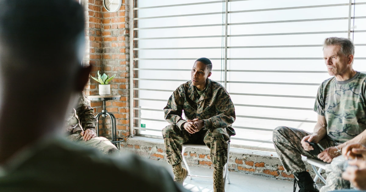 Veterans in military uniforms participating in a group therapy session focused on mental health and peer support.