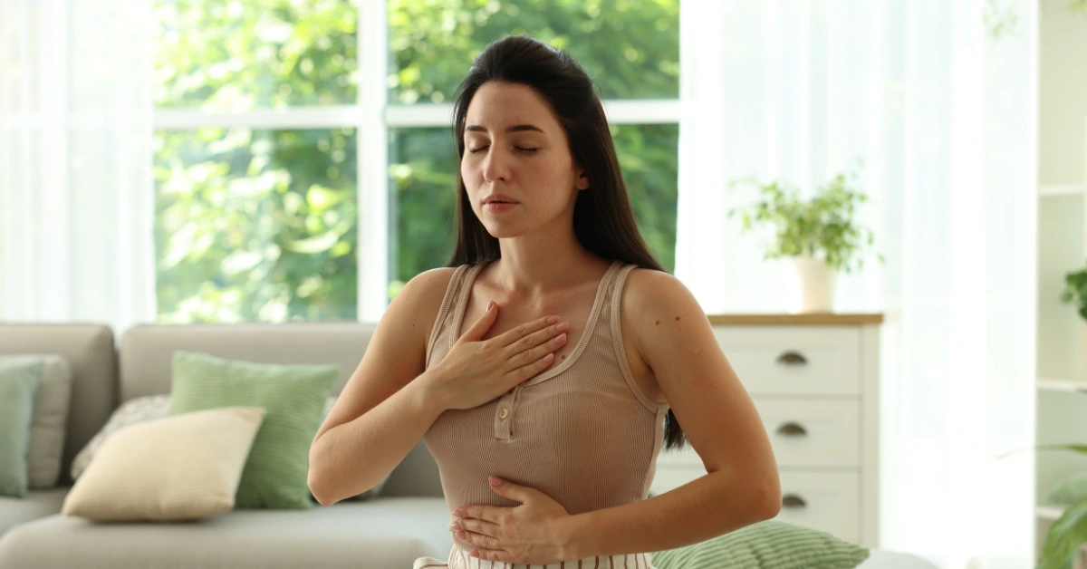 Woman practicing deep breathing with one hand on her chest and one on her abdomen, illustrating coping techniques for panic attacks and anxiety attacks.
