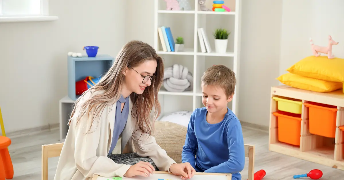 Child therapist working one-on-one with a young boy during a pediatric mental health counseling session in a play therapy room.