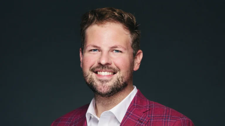 Brandon Morehead smiling in a red plaid jacket