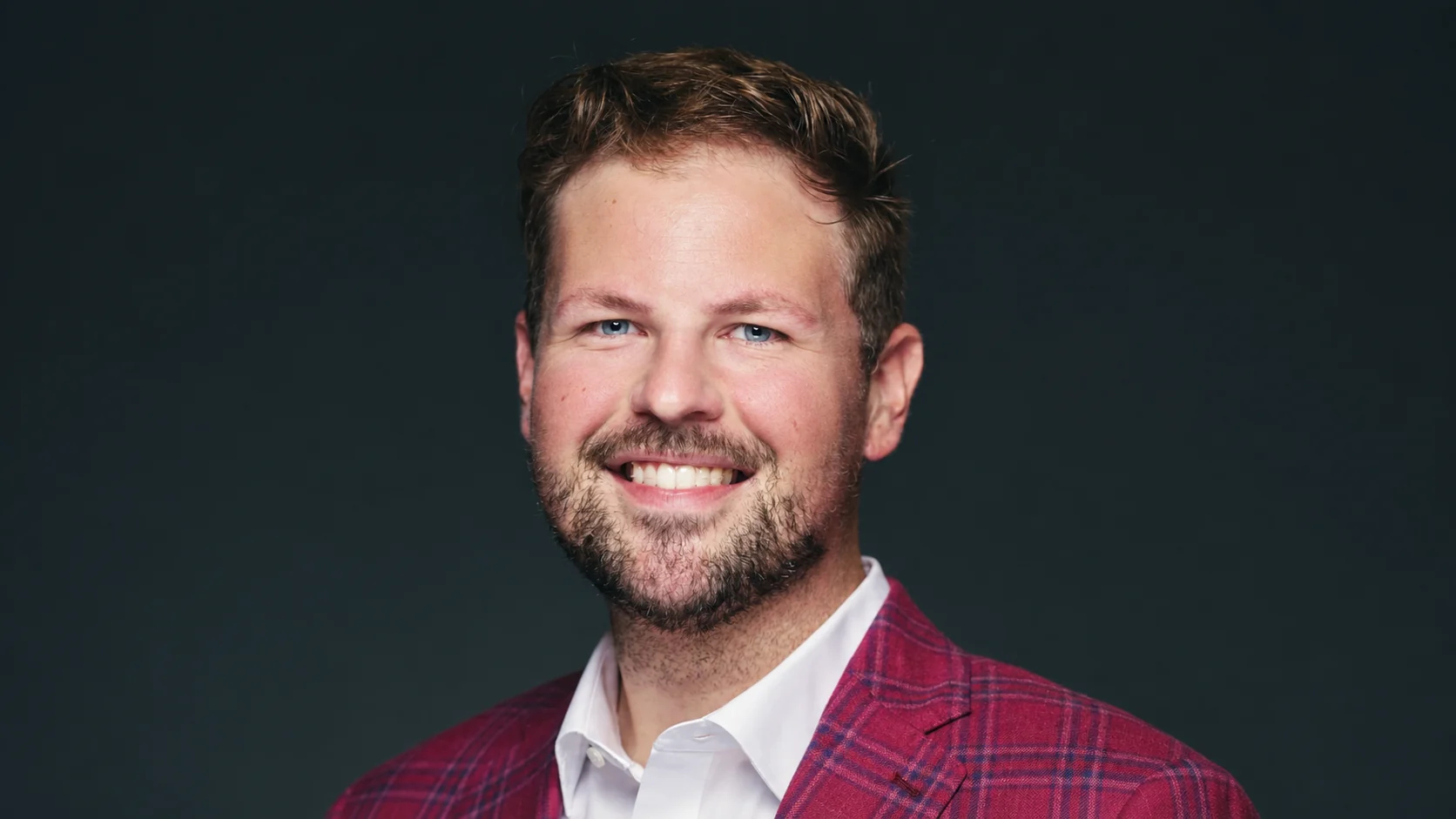 Brandon Morehead smiling in a red plaid jacket