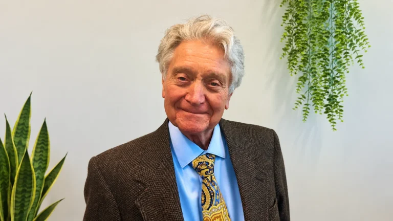 Dr. Ronald Ron Kelley smiling in a brown suit and colorful tie