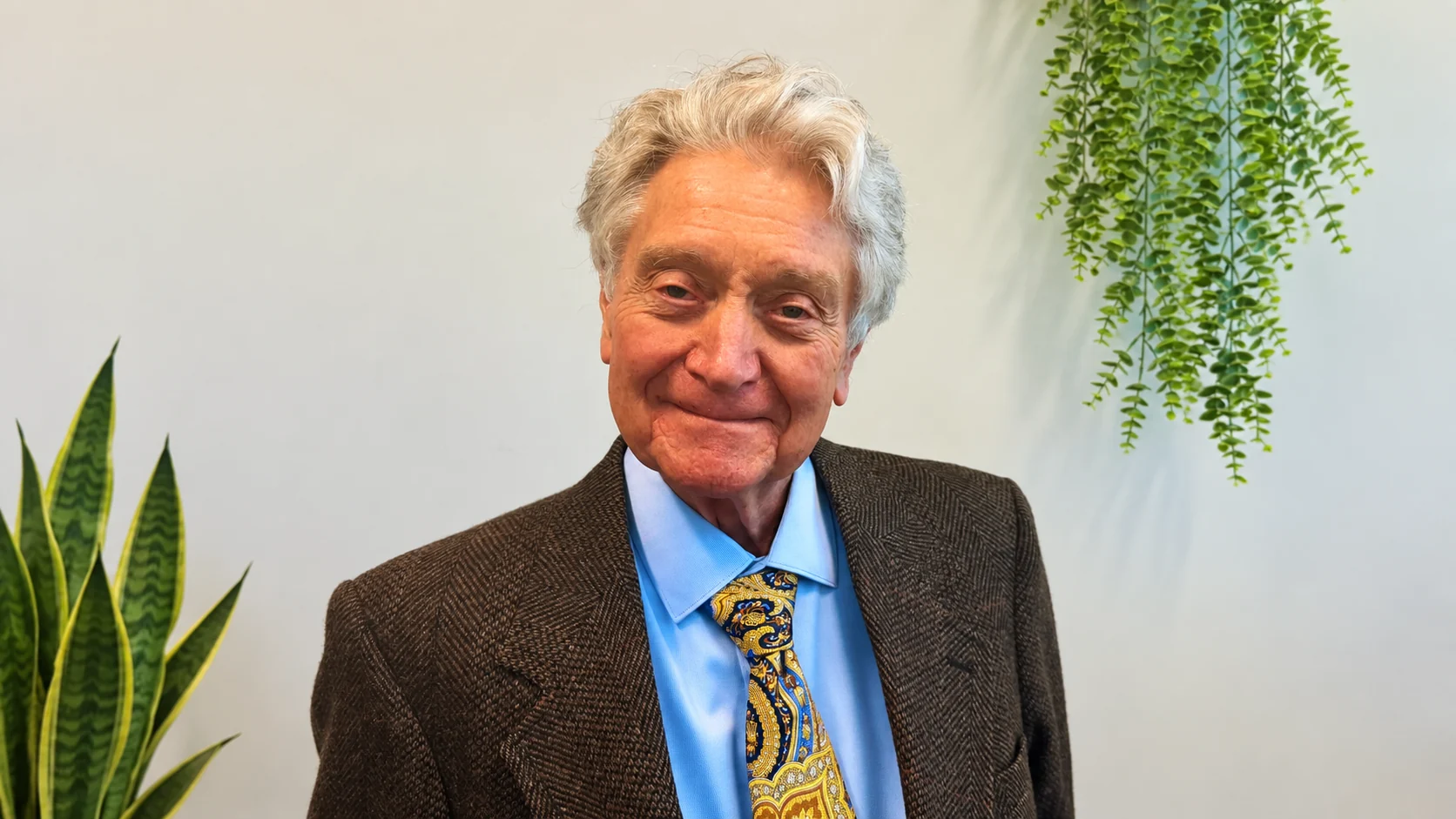 Dr. Ronald Ron Kelley smiling in a brown suit and colorful tie
