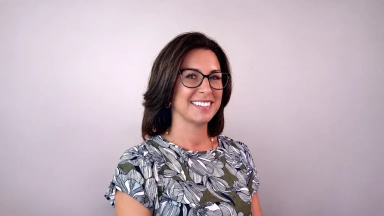 Kylee Gobin smiling in glasses and a floral blouse
