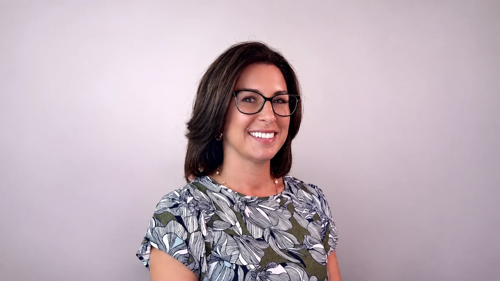 Kylee Gobin smiling in glasses and a floral blouse